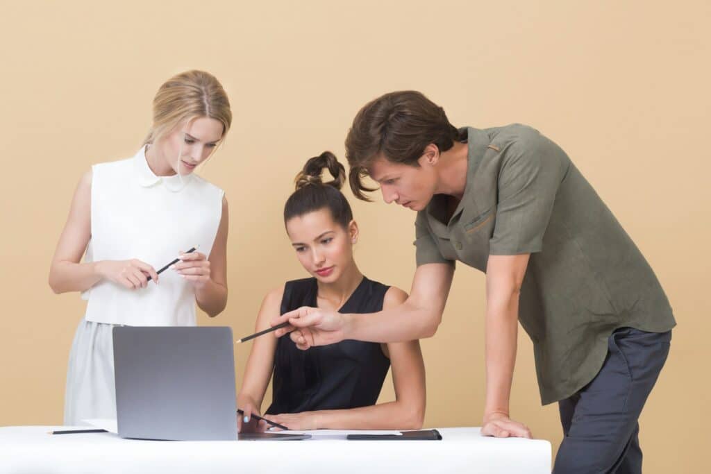 man teaching woman while pointing on gray laptop